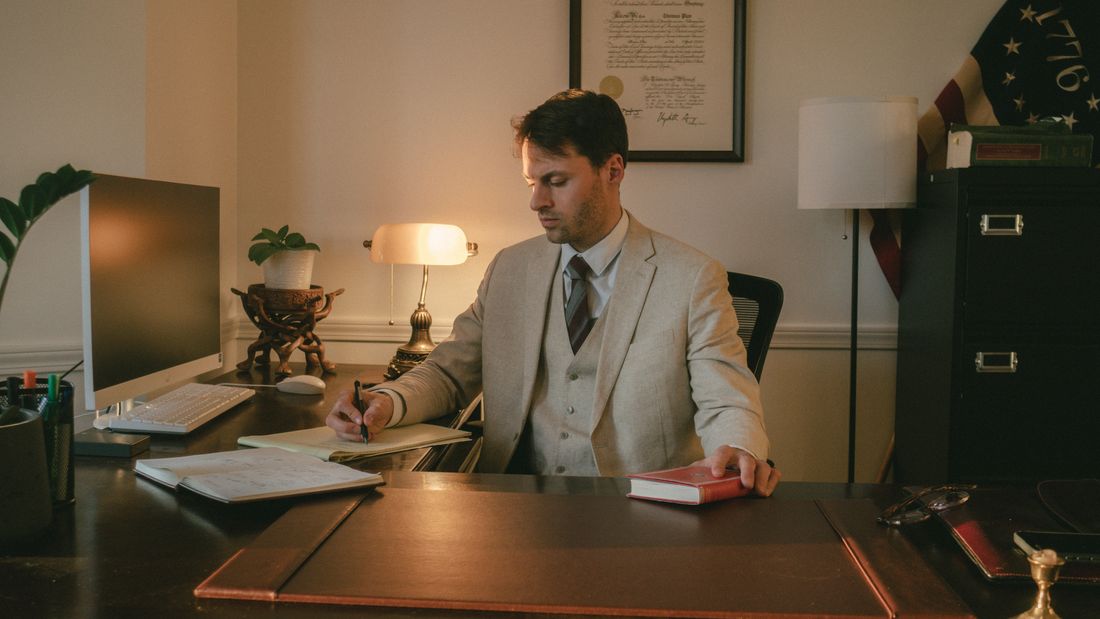 Thomas Plan schreibt an seinem Schreibtisch im Büro.